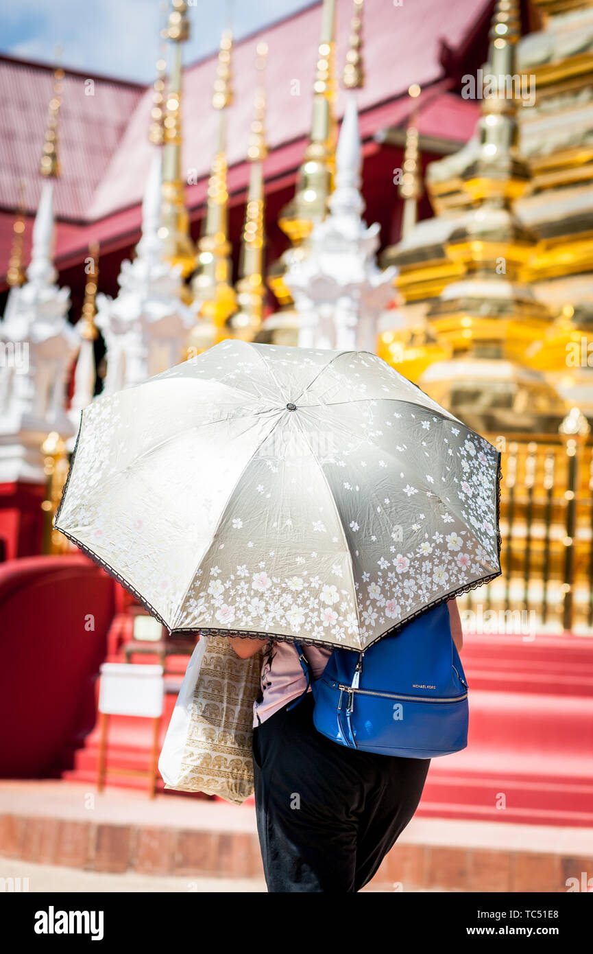 Une femme thaïlandaise tient un parapluie pour se protéger du soleil au  Temple Wat Phra Sing, Chiang Mai, Thaïlande Photo Stock - Alamy