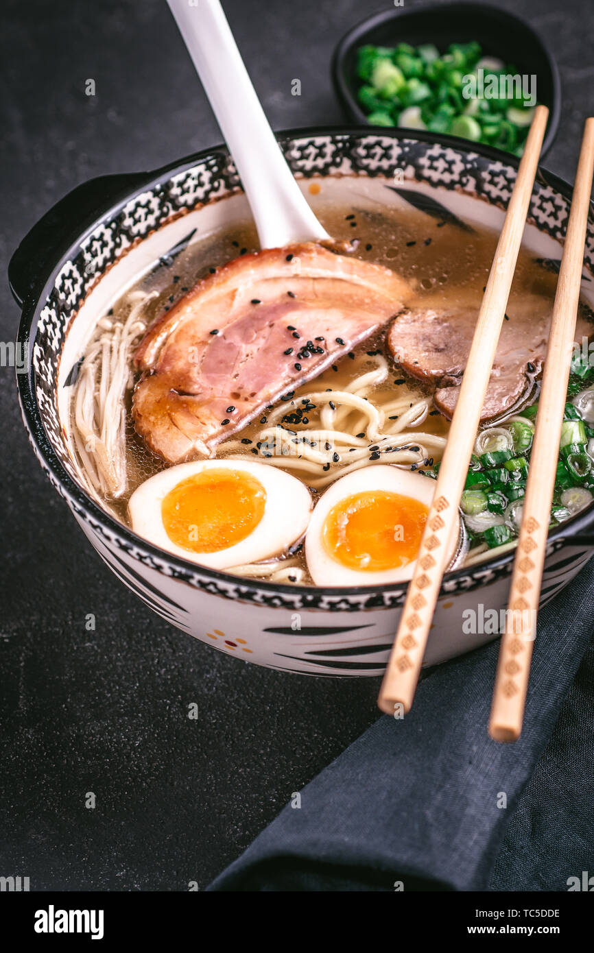 Nouilles Udon à la Soupe de Ramen japonais avec du porc, Œufs et Scallion sur fond sombre Banque D'Images