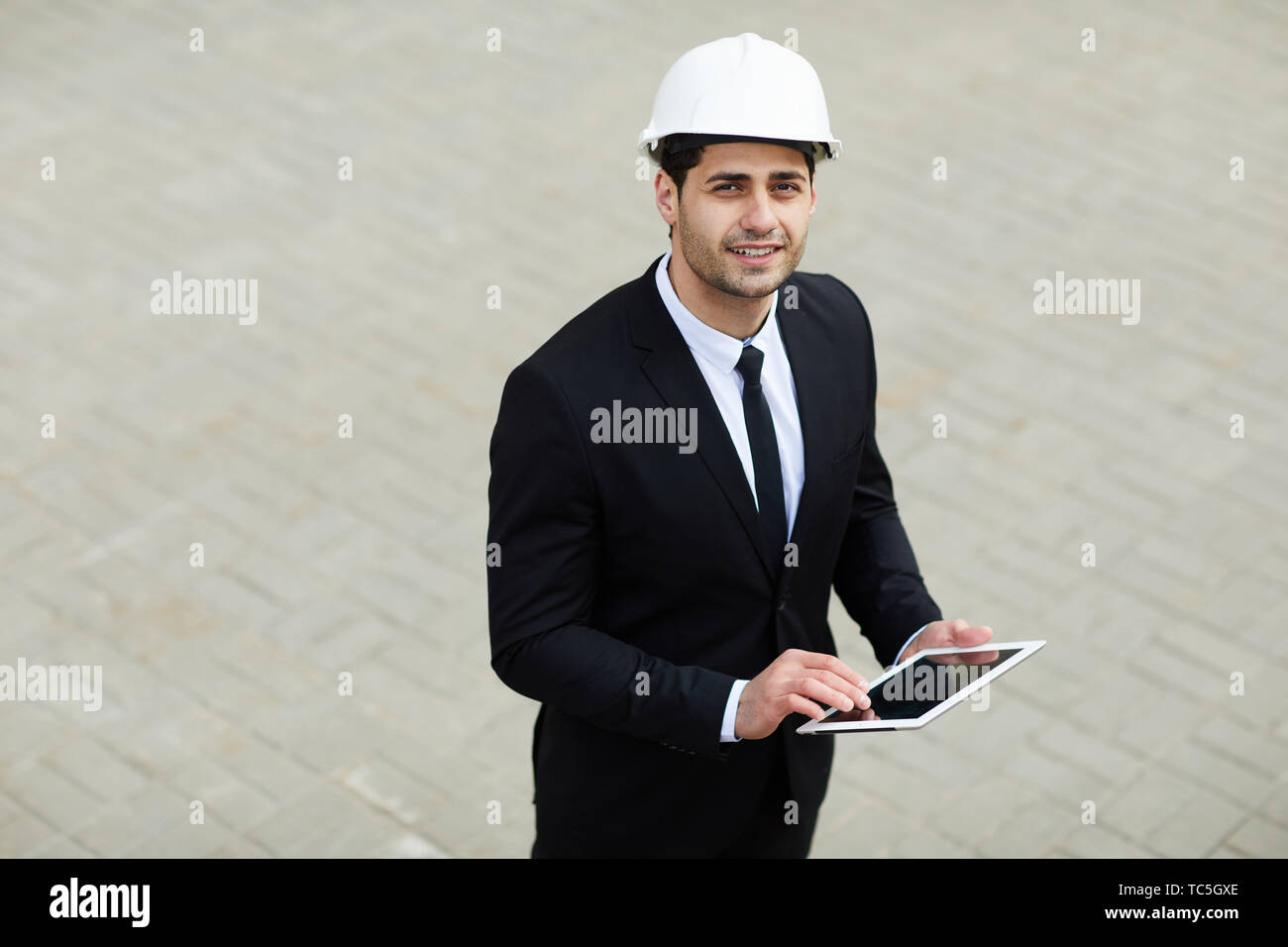 High angle portrait of handsome businessman wearing hardhat Du Moyen-Orient à la recherche jusqu'à l'appareil photo, copy space Banque D'Images