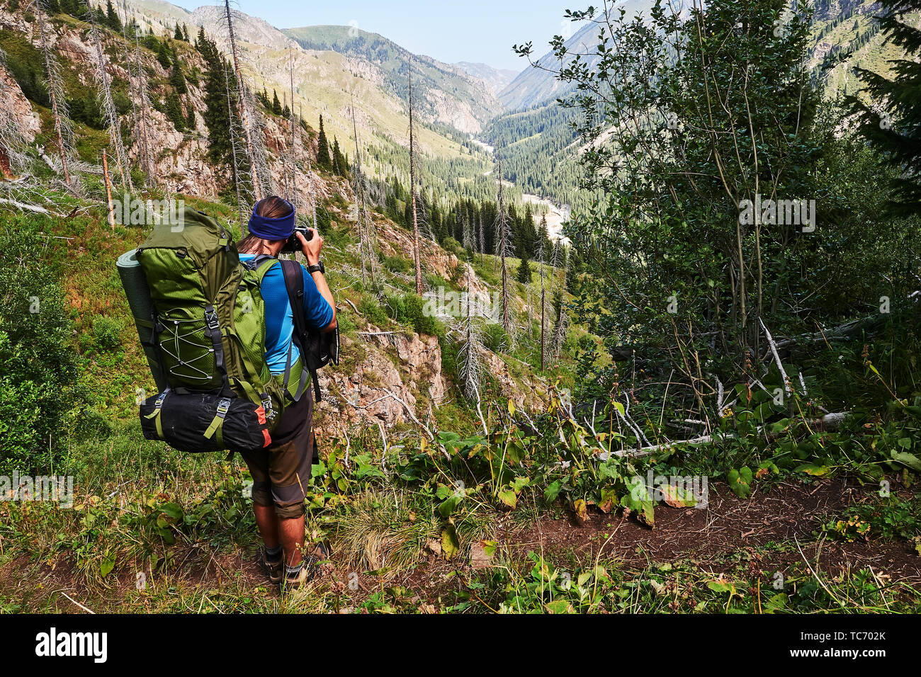 Jeune homme avec sac à dos sur le dessus, prendre une photo de la montagne de la gorge. Guy en chemise bleue prendre photo de montagne durant le voyage autour de Kazakhstan. Vi Banque D'Images