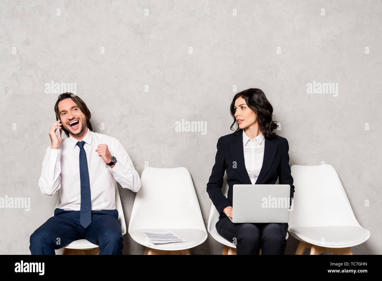 Attractive Woman with laptop looking at happy man talking on smartphone Banque D'Images