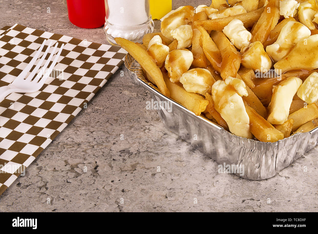 La poutine dans un récipient pour emporter. Cuite avec des frites, de la sauce et du fromage. Une cuisine canadienne. Banque D'Images