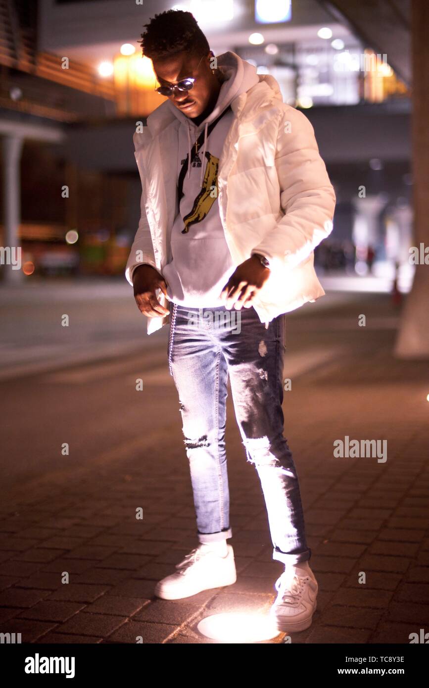 Jeune homme africain debout dans la lumière à street en ville la nuit, à Munich, Allemagne Banque D'Images