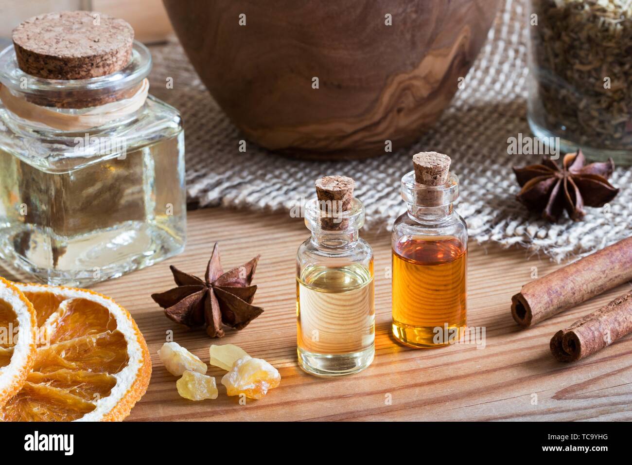 Bouteilles d'huile essentielle avec l'anis étoilé, cannelle, encens et des tranches d'orange séchée. Banque D'Images