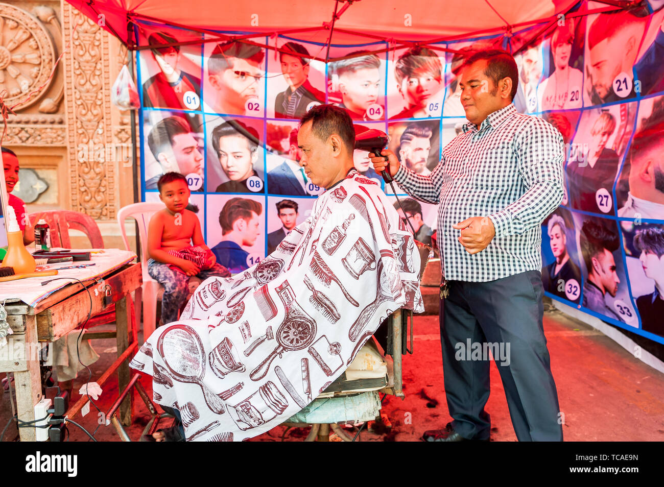 Un homme cambodgien a coupé ses cheveux dans un barbershop typique en plein air à Phnom Penh, au Cambodge. Banque D'Images