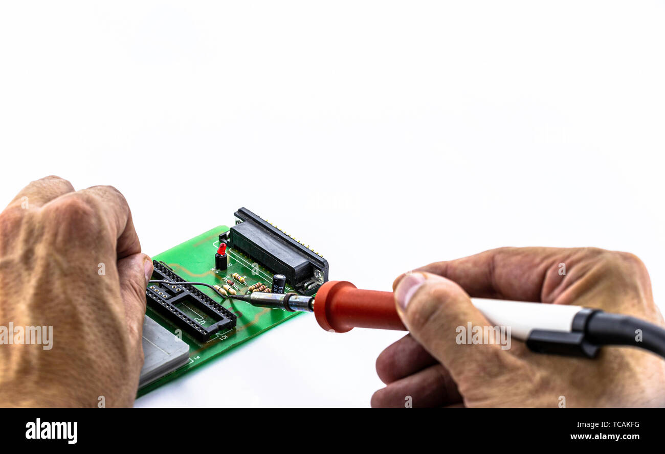 Souder les mains des hommes de composants sur un circuit imprimé à l'aide de l'étain et un fer à souder. Réparation de l'électronique. Selective focus Banque D'Images