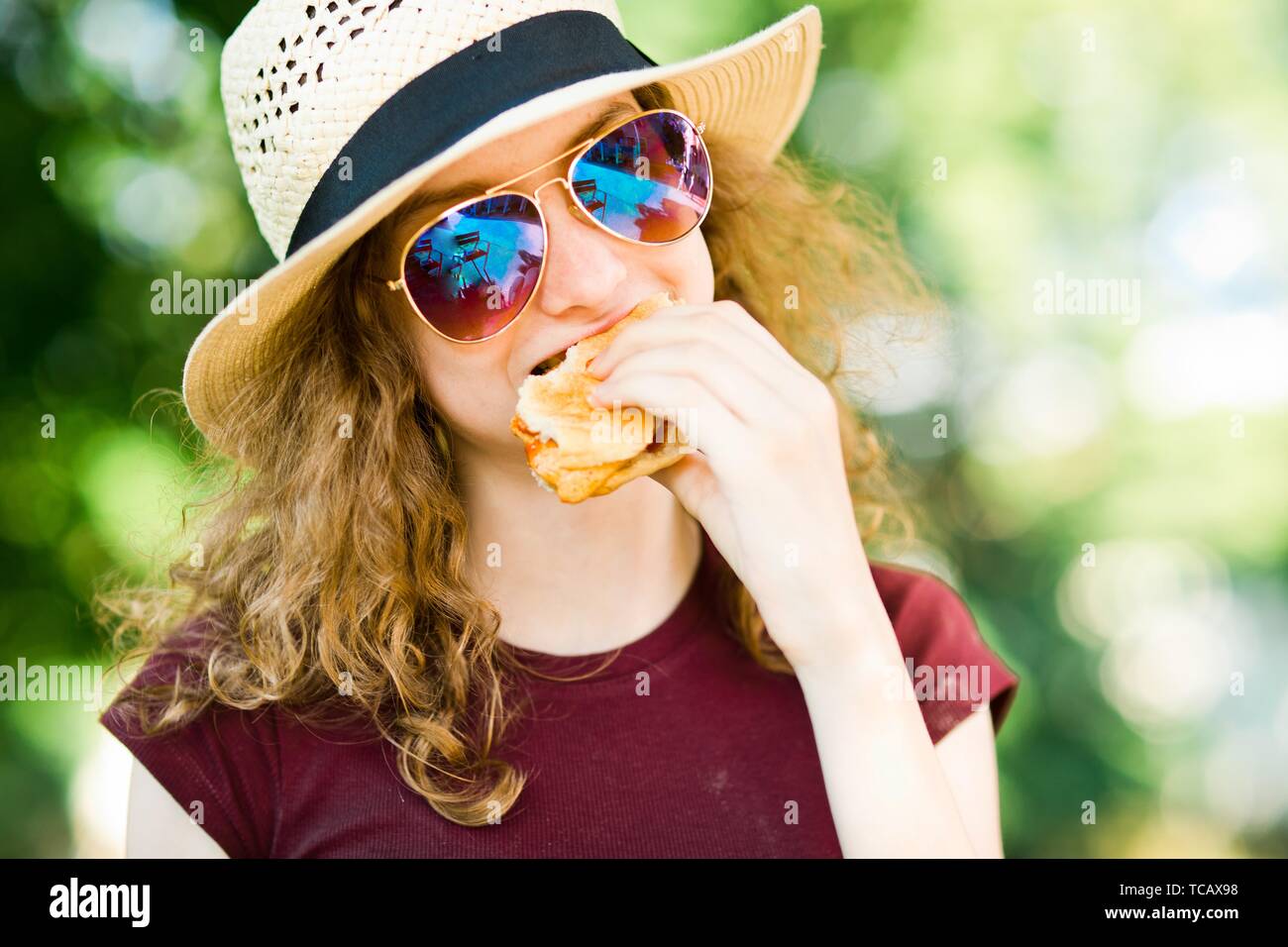 Une jeune fille en chapeau avec des lunettes de soleil les yeux dans la nature en plein air d'hamburger. Banque D'Images