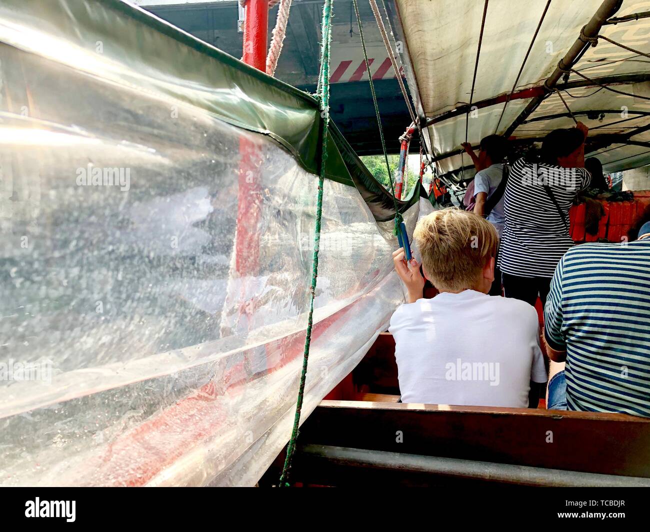 Garçon blond dans le choix du bateau, il tenir la robe pour tirer vers le haut pour protéger la toile transperence splash venez à l'intérieur., Thaïlande San [Sarb cana Banque D'Images