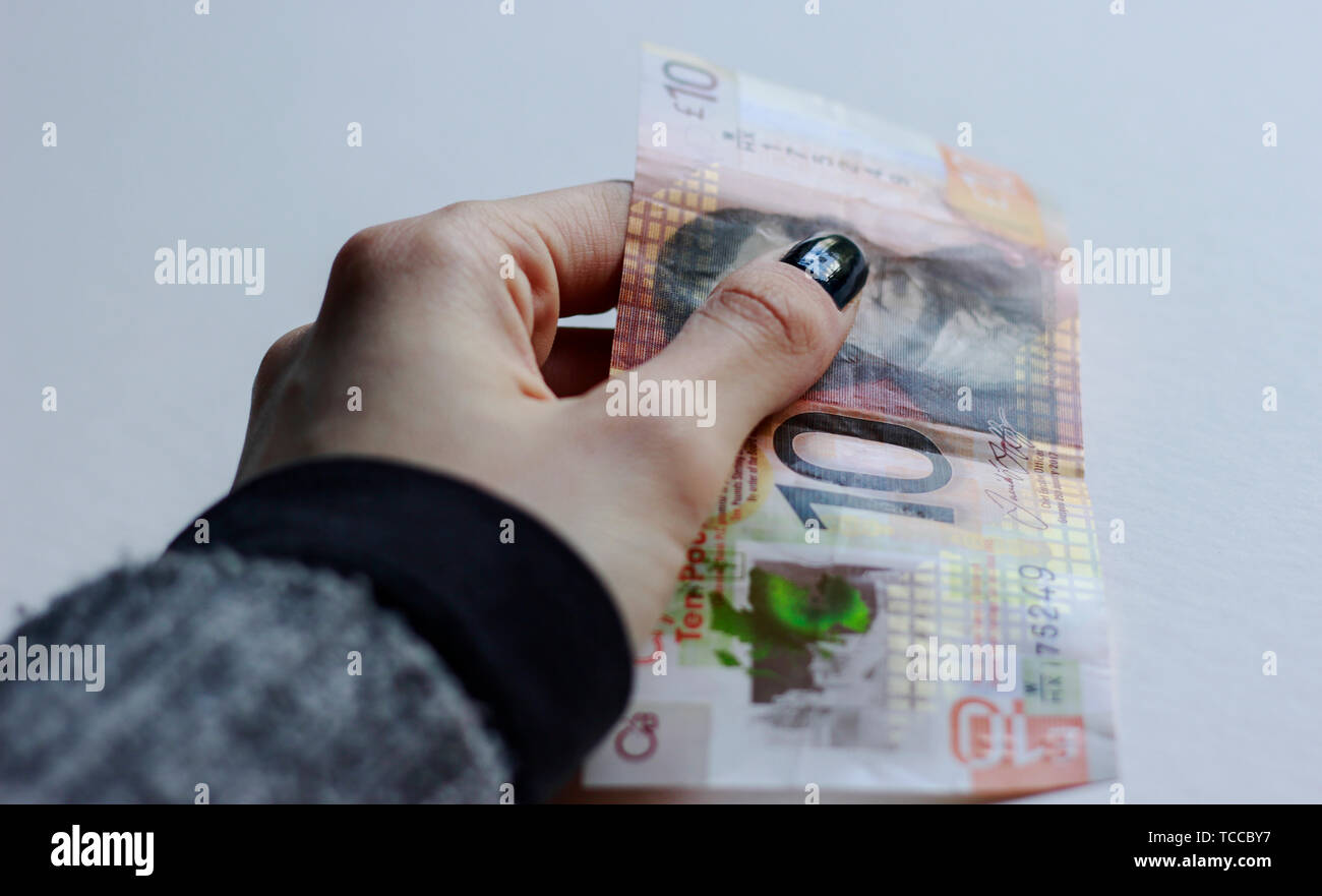 Bank of Scotland €10 note, un tenner, euros de la livre sterling, mai 2019, UK.Woman holding 10 livres plus de billets de banque écossais papier backg isolés Banque D'Images