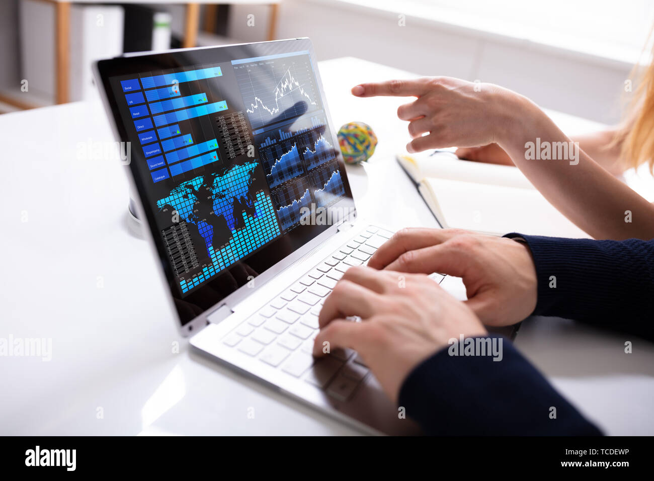 Businesswoman Showing graphique sur un écran d'ordinateur portable à sa collègue, tout en travaillant à l'Office de Tourisme Banque D'Images