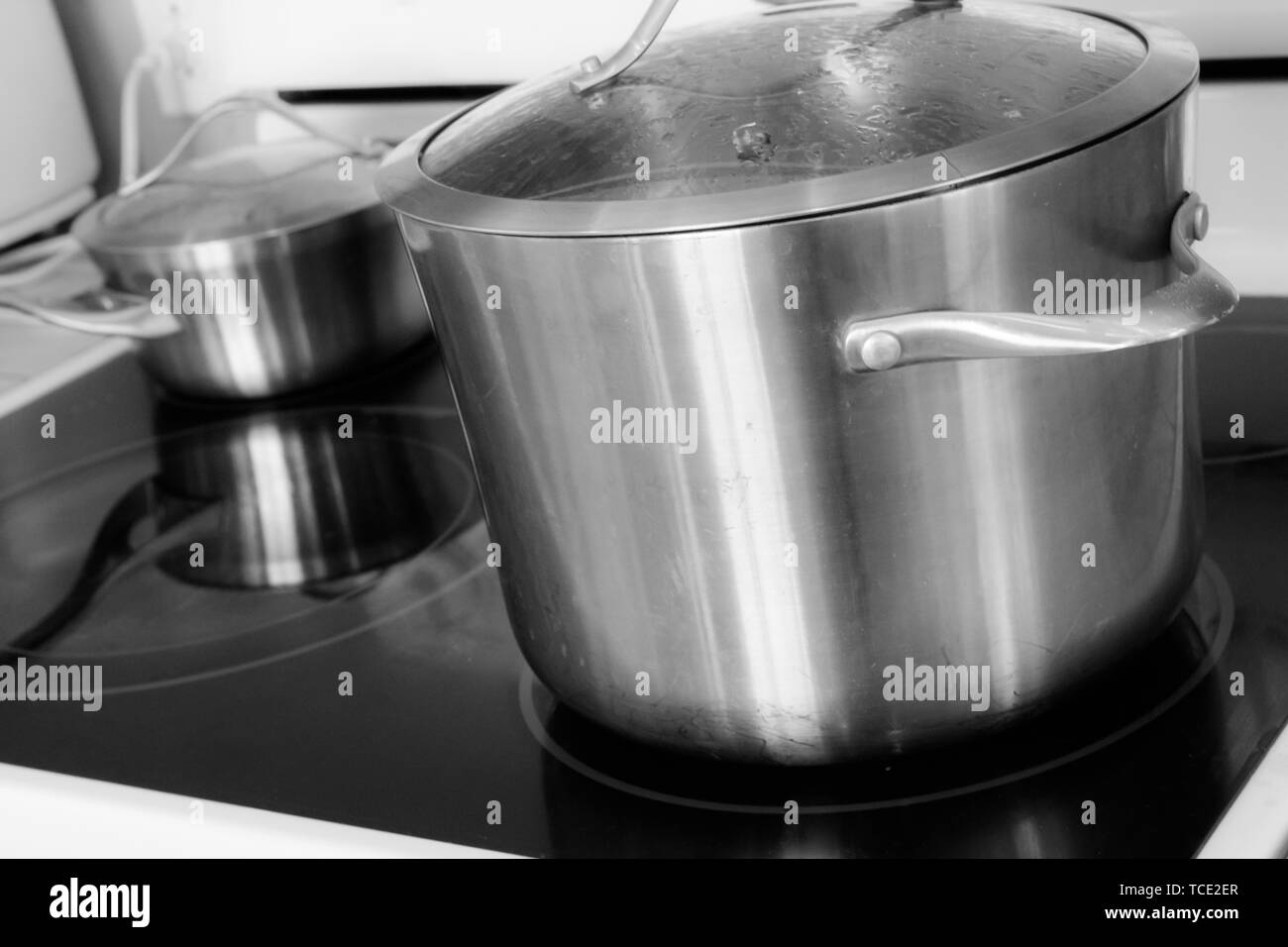 Casseroles en acier inoxydable sur une cuisinière vitrocéramique dans une cuisine domestique. Banque D'Images