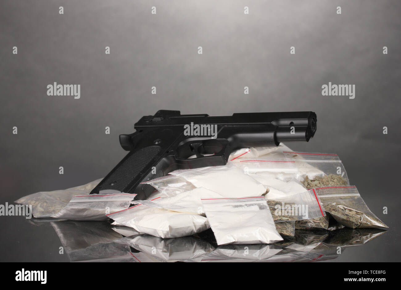 La cocaïne et la marihuana en paquets avec pistolet sur fond gris Banque D'Images