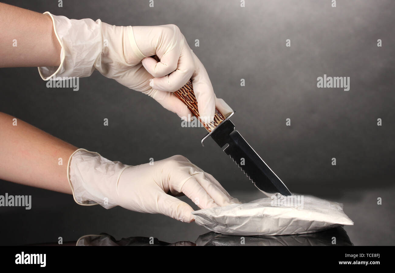L'ouverture des paquets de cocaïne à l'aide d'un couteau sur fond gris Banque D'Images