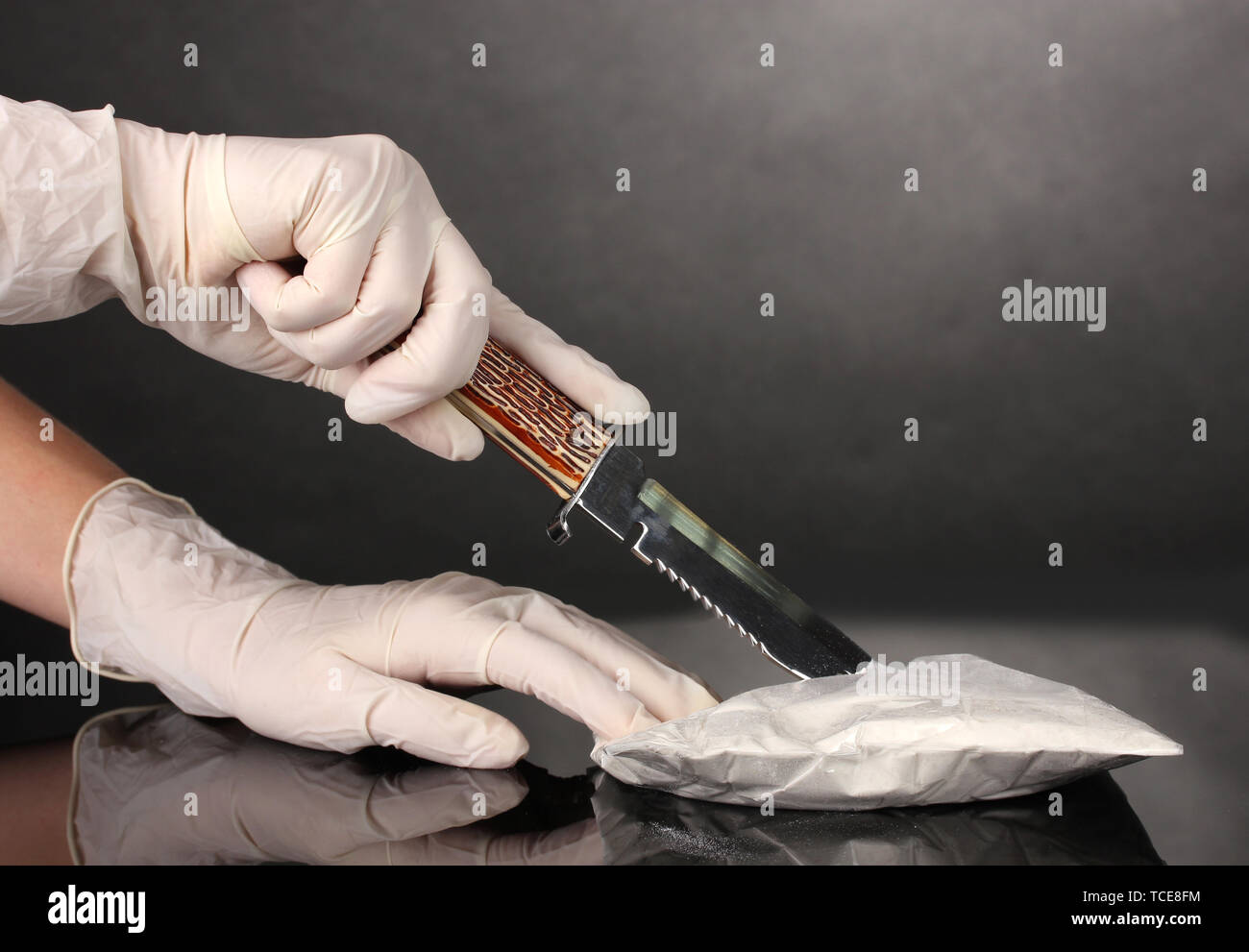 L'ouverture des paquets de cocaïne à l'aide d'un couteau sur fond gris Banque D'Images