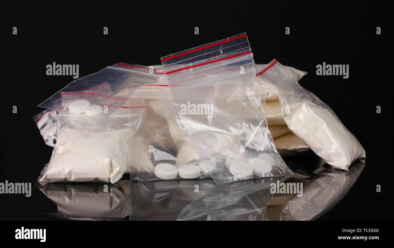 La cocaïne et les drogues dans des paquets sur fond noir Banque D'Images