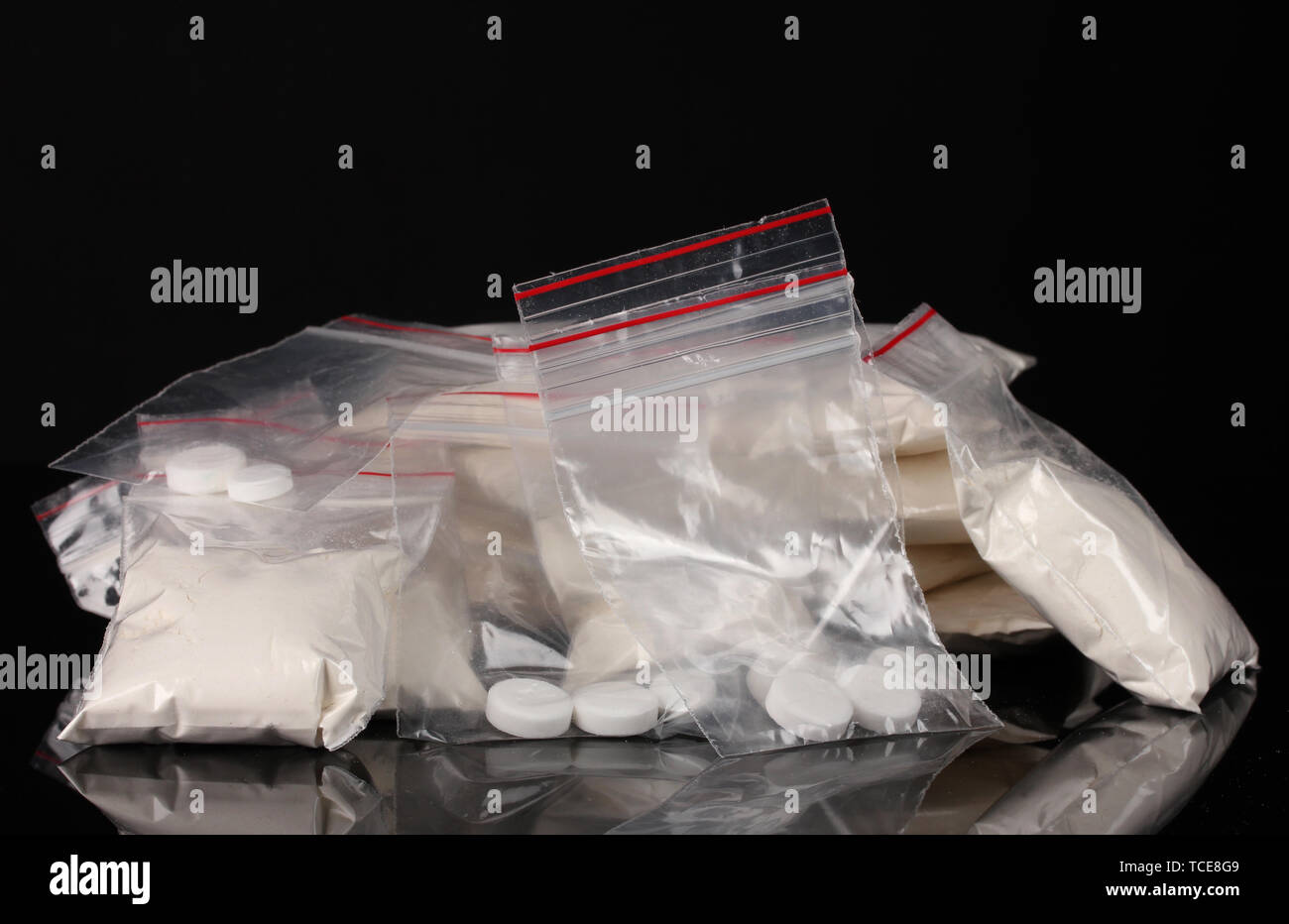 La cocaïne et les drogues dans des paquets sur fond noir Banque D'Images