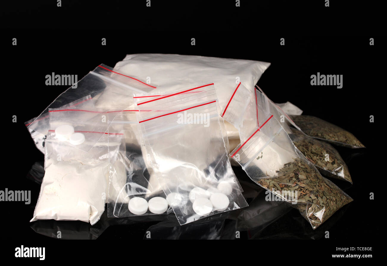 La cocaïne et la marihuana en paquets sur fond noir Banque D'Images