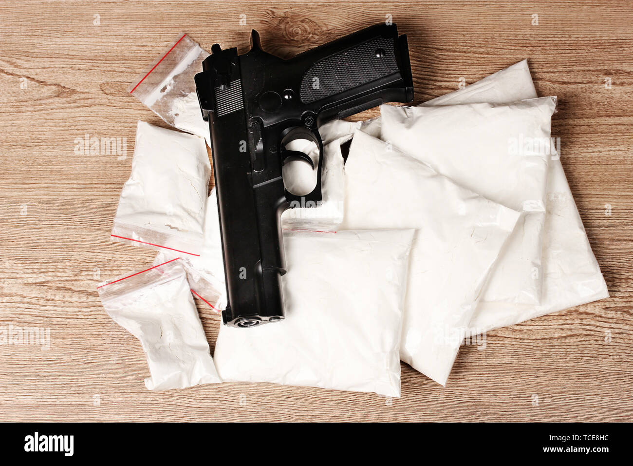 La cocaïne en paquets avec pistolet sur fond de bois Banque D'Images