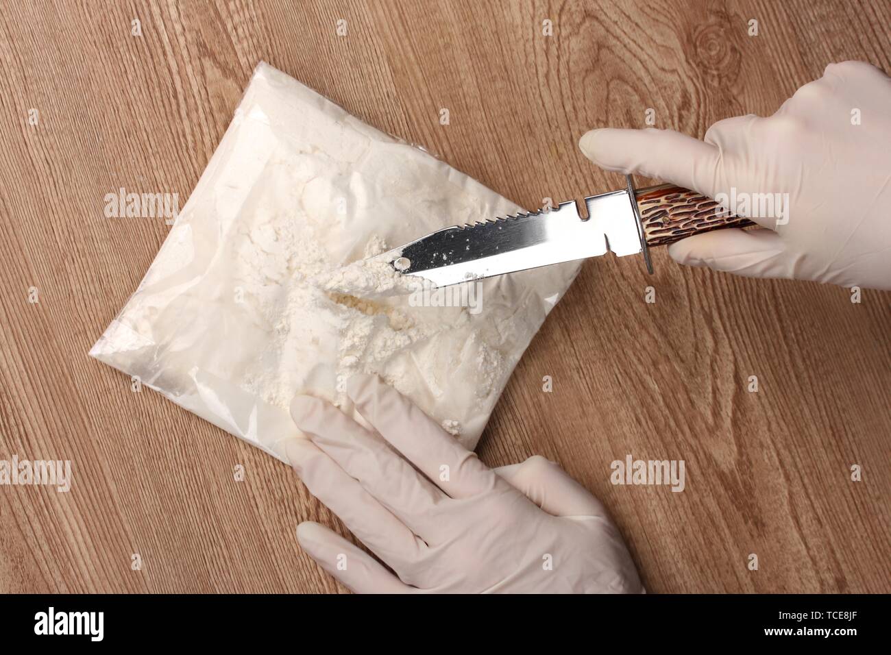 L'ouverture des paquets de cocaïne à l'aide d'un couteau sur la table en bois Banque D'Images