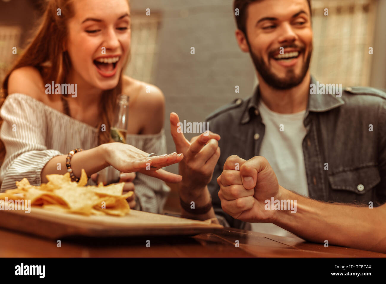Une soirée entre amis. Photo en gros plan d'appel lumineux rayonnant sourire les jeunes-adultes amis partageant un rire et jouer à des jeux tout en étant assis à t Banque D'Images