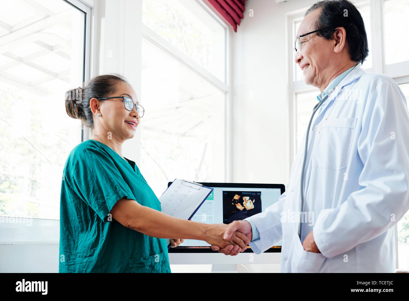 Smiling de cardiologue main tremblante de chirurgienne en vert scrubs Banque D'Images