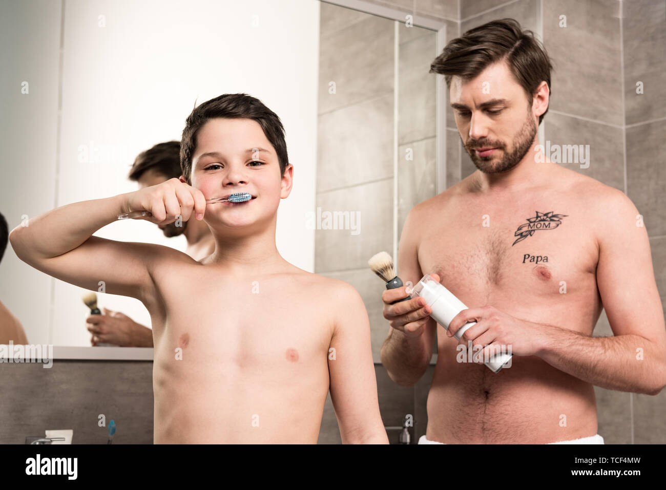 Preteen boy se brosser les dents et père de la mousse à raser et la brosse tenue dans la salle de bains Banque D'Images