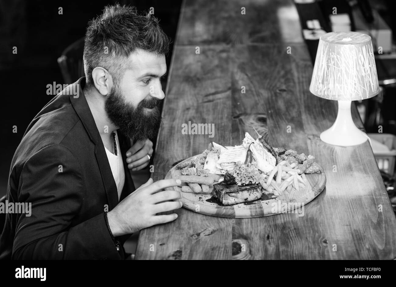 Woman costume formel s'asseoir à comptoir bar. L'homme a reçu de pommes de terre frites repas avec viande et poisson, lavash. Profitez de repas. Il méritent de délicieux repas. Des calories. Vous pourrez vous détendre après une dure journée de travail. Banque D'Images