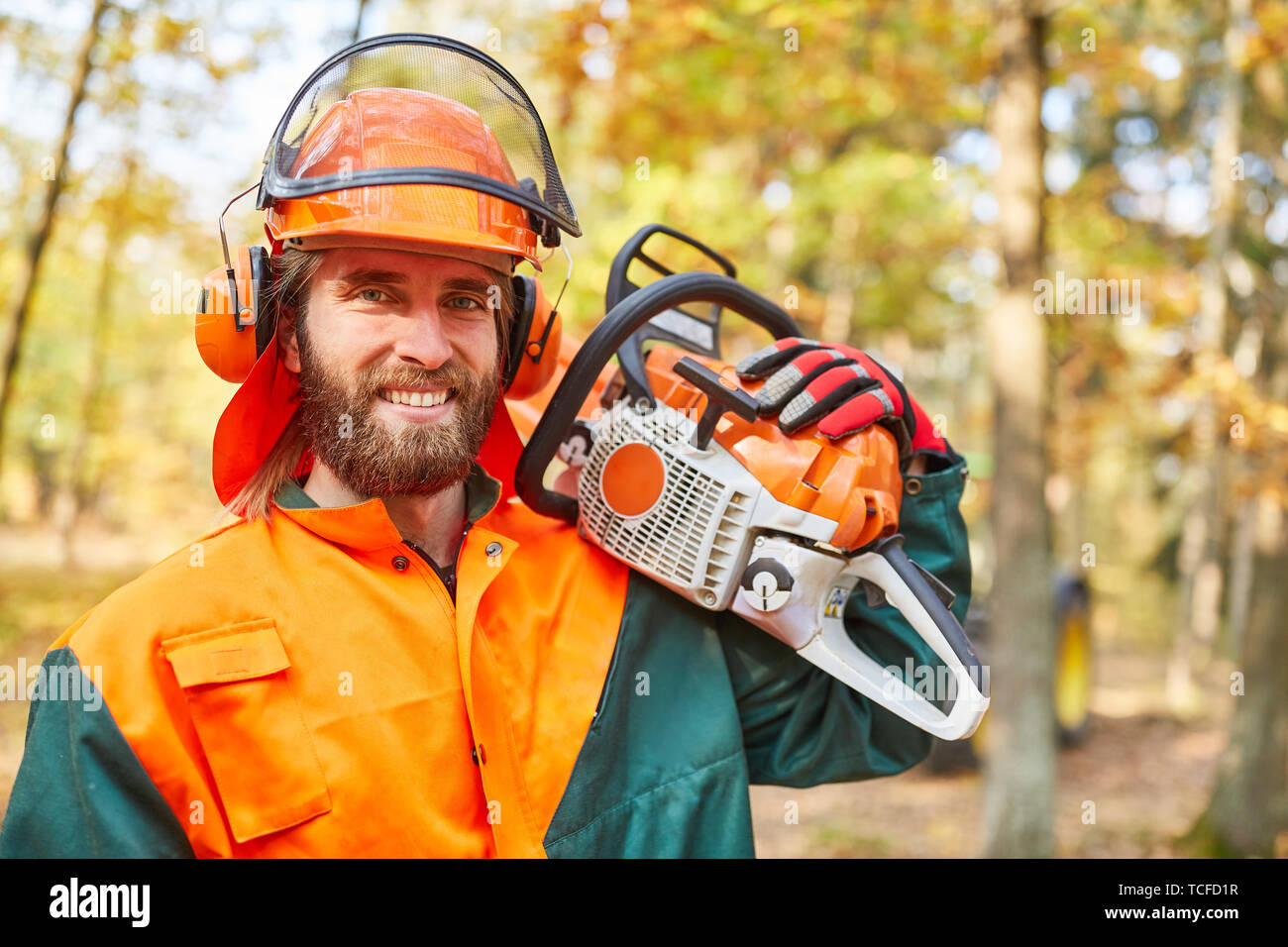 Bûcheron ou travailleur forestier avec tronçonneuse et matériel de protection dans la forêt Banque D'Images