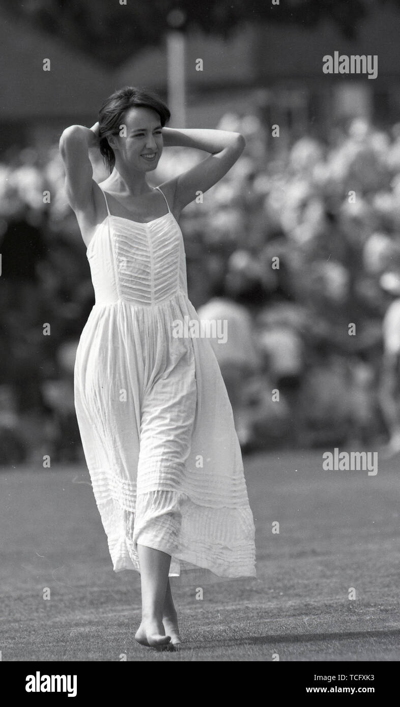 Middlesex CCC à Uxbridge Cricket 1990 Une jeune femme jouant sur le terrain pendant la pause déjeuner dans un fluide en robe d'été blanche. Photo par Tony Henshaw Banque D'Images