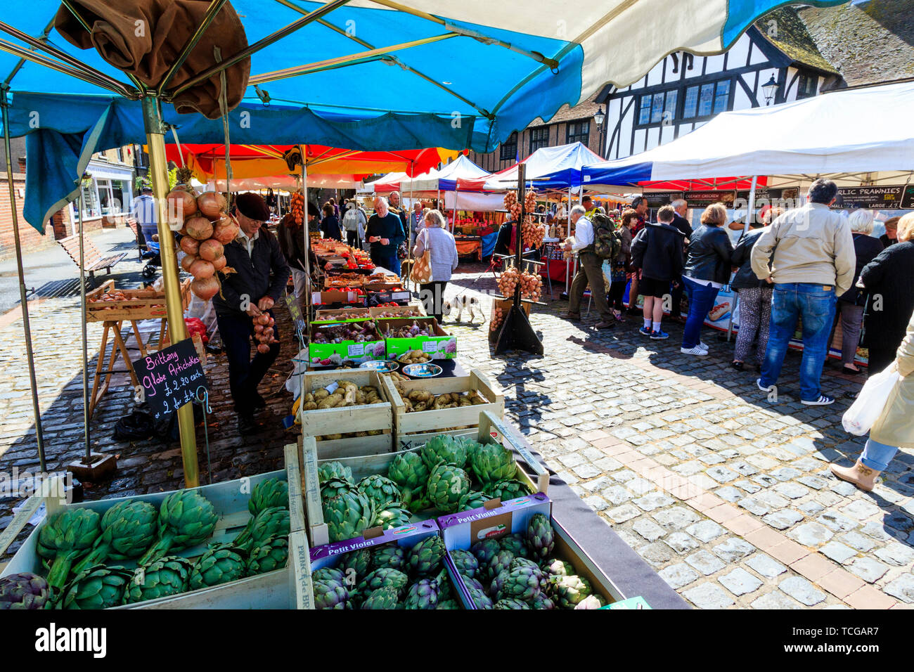 Le marché français de l'événement week-end à Sandwich, en Angleterre. Épicier vert français en décrochage de la Vieille-Ville, l'ensoleillement, les gens. Les légumes en premier plan sur l'étal. Guildhall médiévale en arrière-plan. Banque D'Images