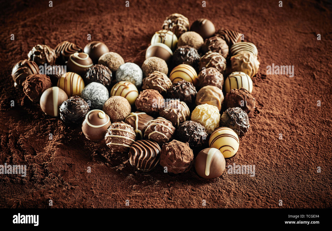 Plusieurs articles en chocolat noir et blanc, les bonbons en forme de coeur assis sur mat de cacao poudre Banque D'Images