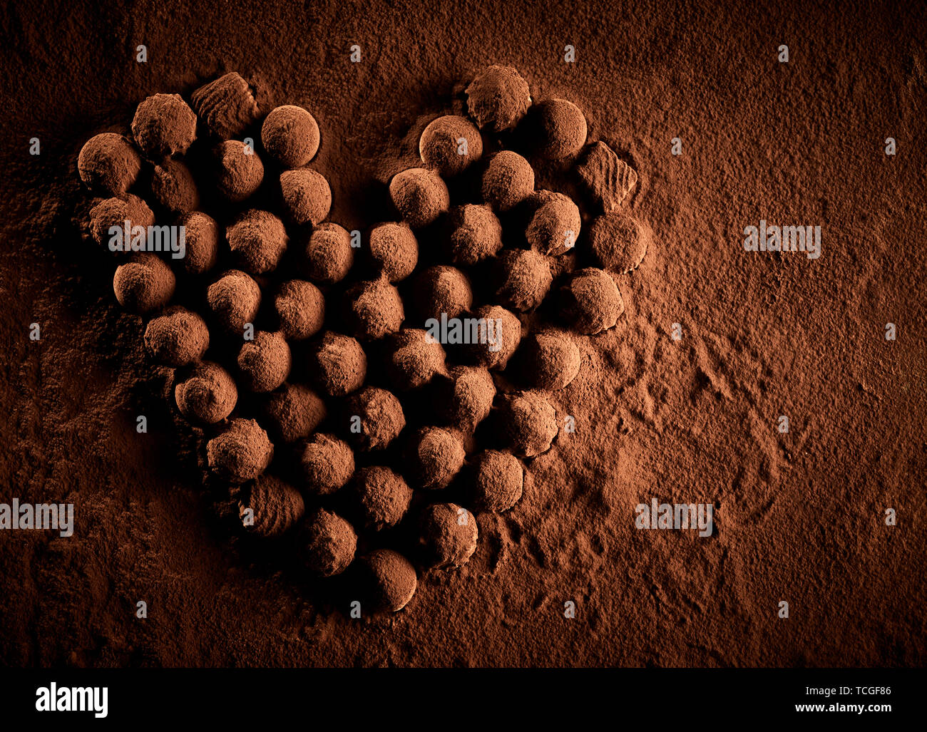 Recouvert de poudre de cacao chocolats placés dans la formation en forme de coeur pour symboliser la romance plus de poussière brune Banque D'Images