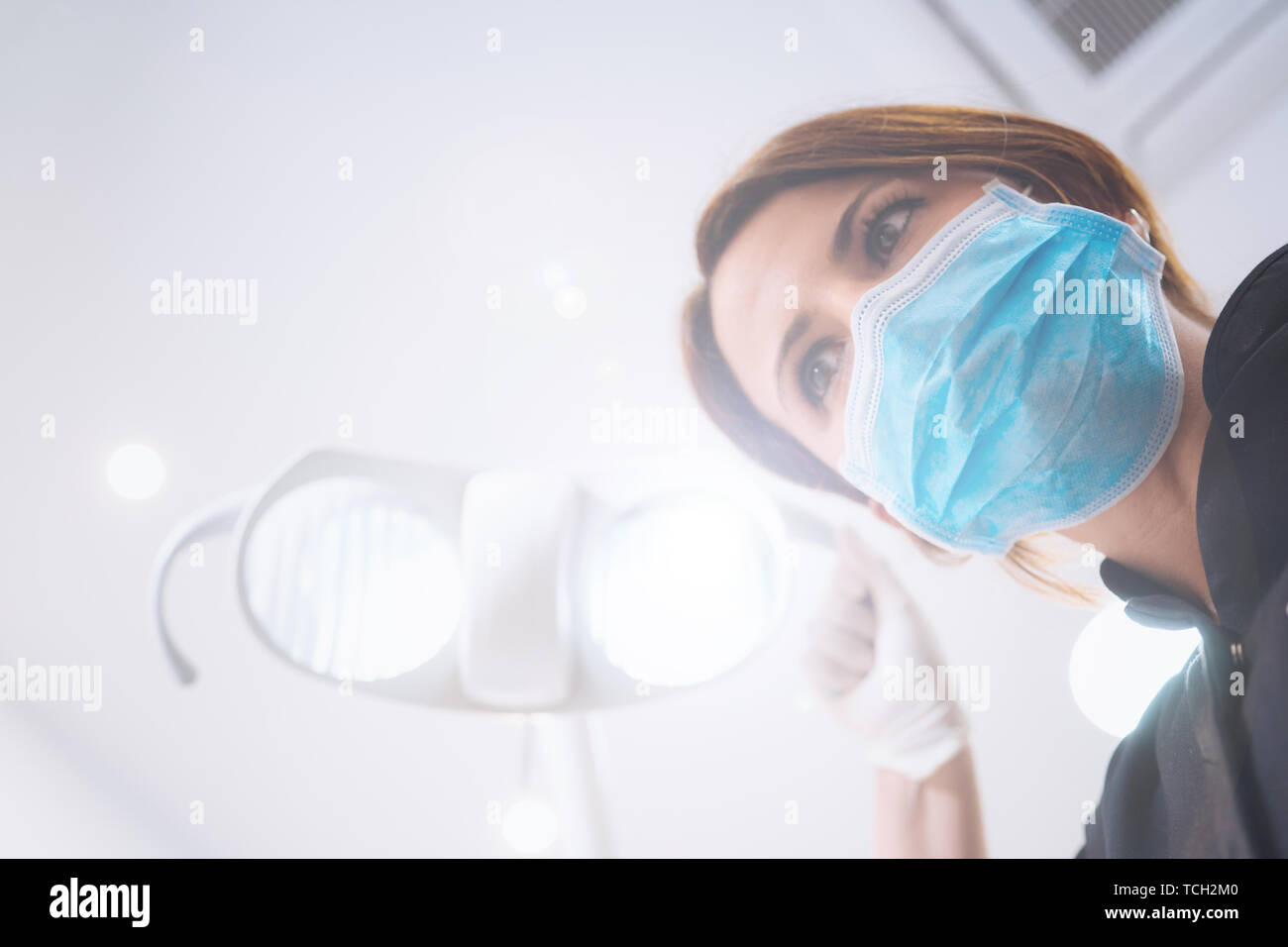 Vue de dessous de deux femmes dentistes dans le masque chirurgical et outils de maintien à l'appareil photo à. Point de vue du patient au dentiste. Banque D'Images