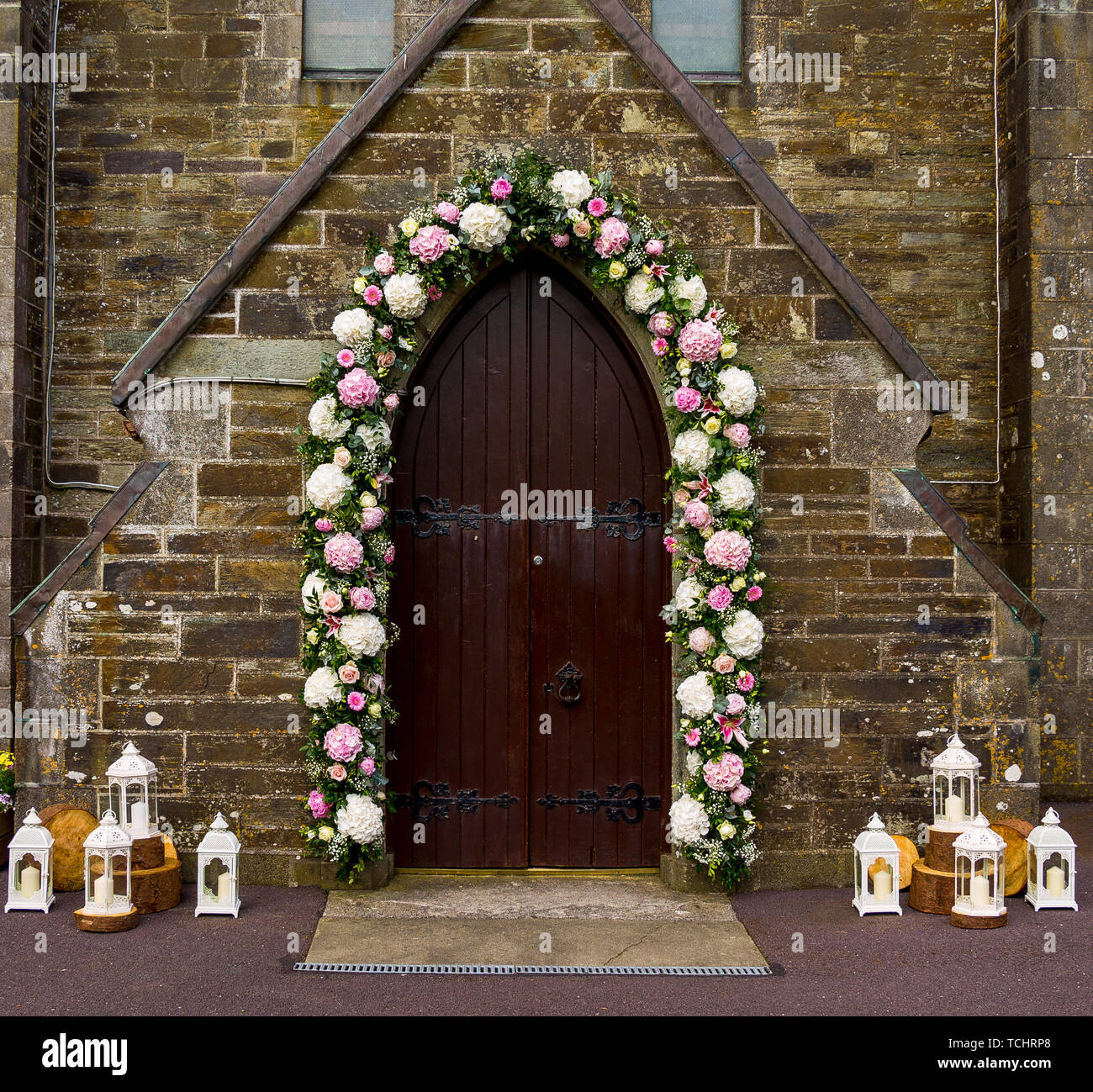 Fleurs de mariage autour d'une porte de l'église Banque D'Images