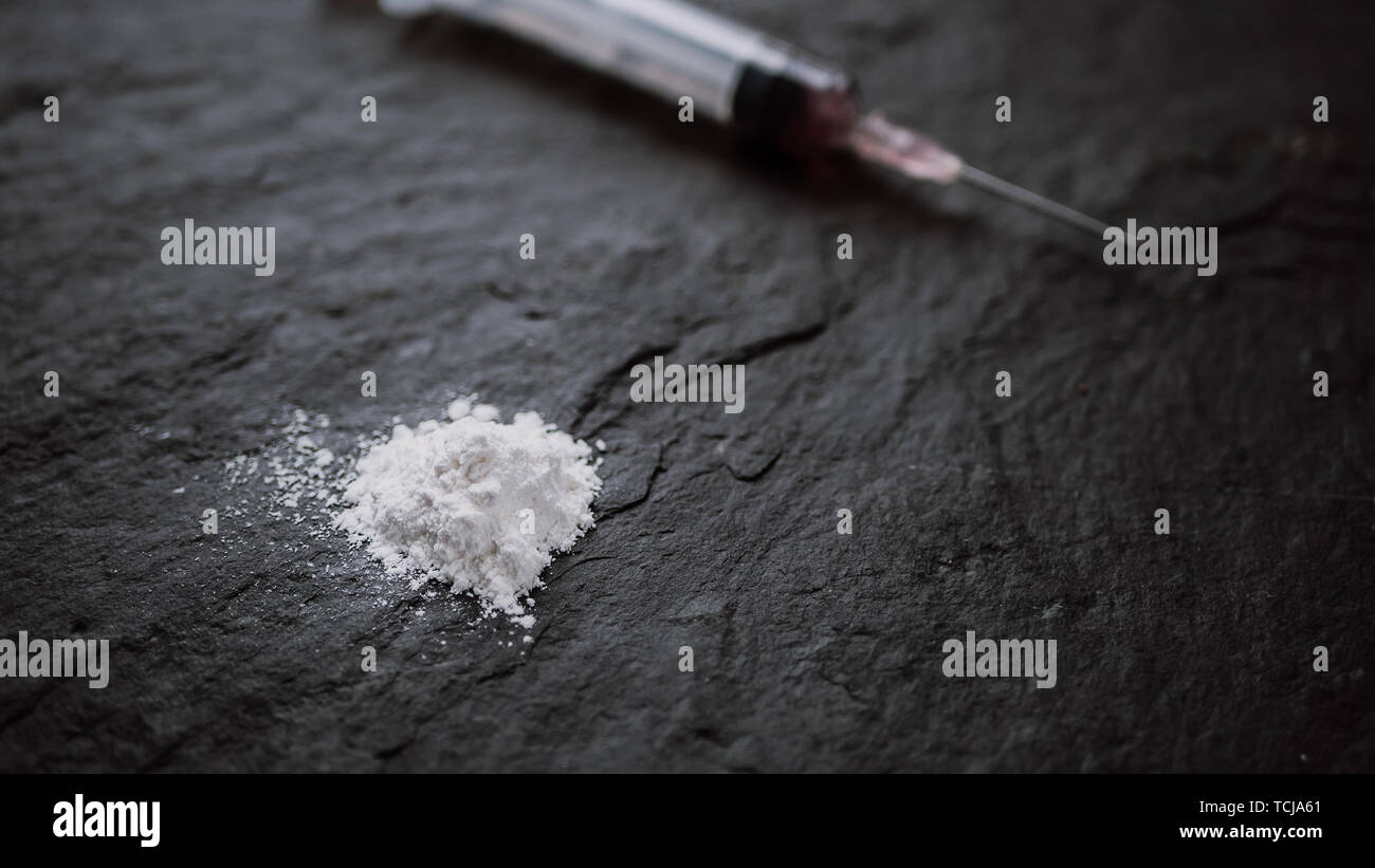 Toxicomane concept. close up de la seringue et l'héroïne cuit sur fond noir Banque D'Images