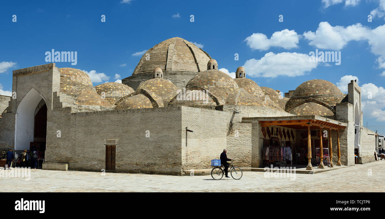 Marguilan, Boukhara, Ouzbékistan - 25 avril 2019 : Les hommes de vendre du pain ouzbek, lepeshka ou non, à le transporter sur un vélo, à l'arrière-plan Zargaro Toqi Banque D'Images