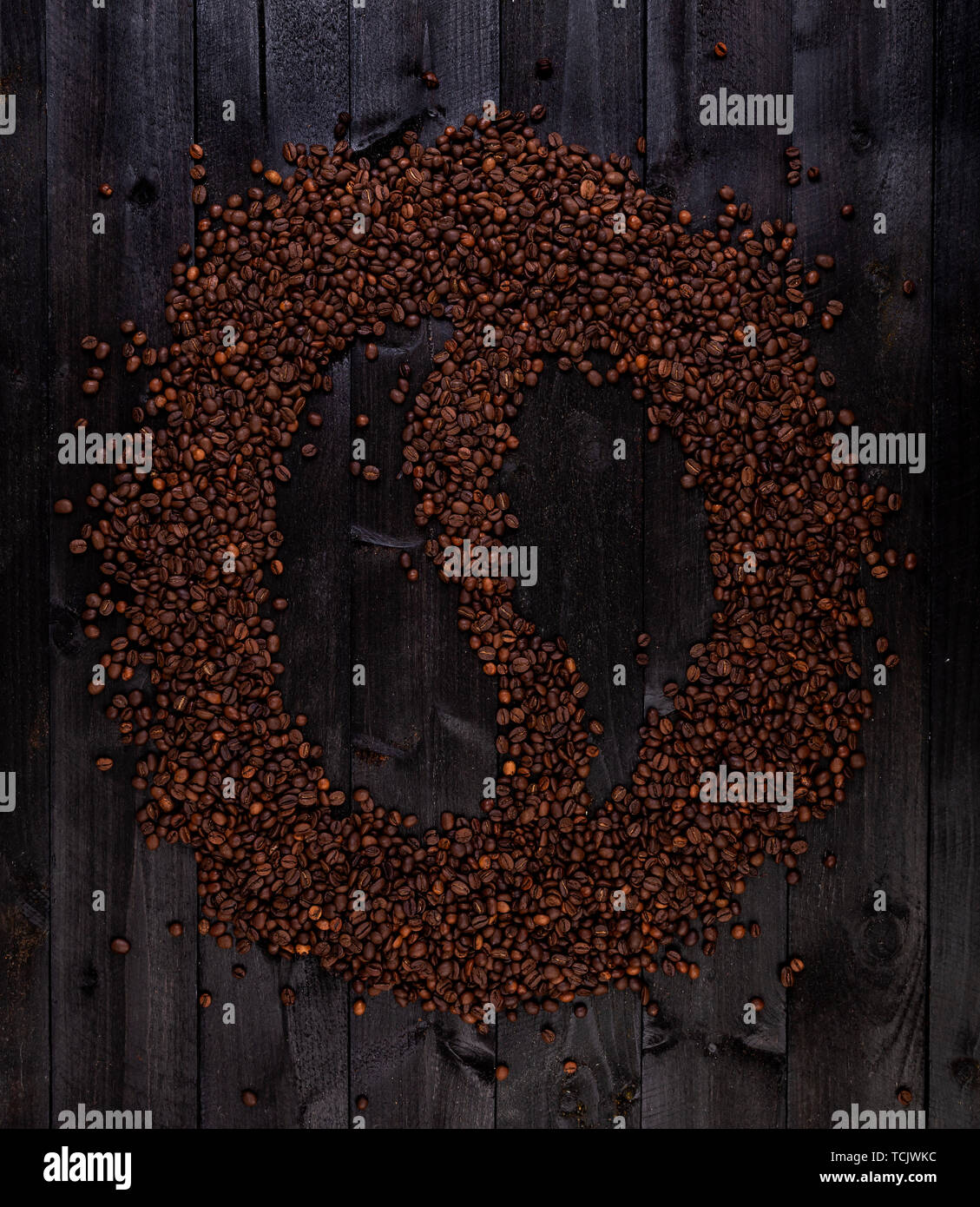 Symbole du café en grains de café torréfiés sur un fond en bois noir Banque D'Images