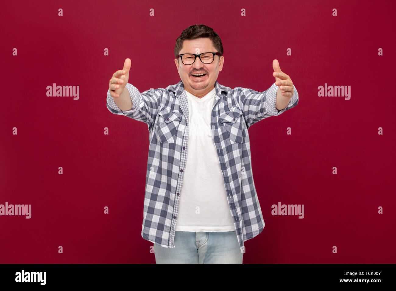 Portrait of happy heureux de voir handsome middle aged man in casual chemise à carreaux et des lunettes à pleines dents, sourire permanent et souhaitez hugging Banque D'Images