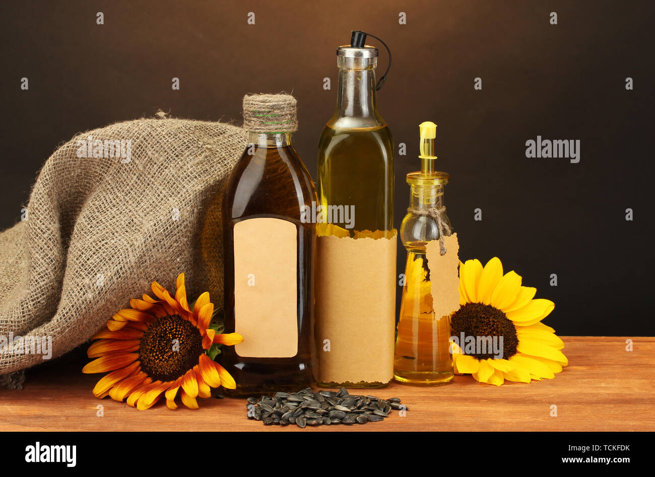 En bouteilles d'huile, de tournesol et de graines, sur table en bois sur fond brun Banque D'Images