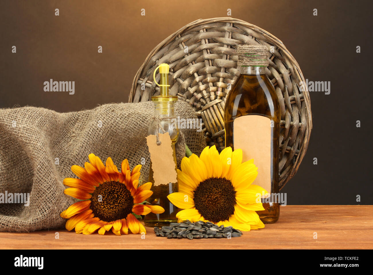 En bouteilles d'huile, de tournesol et de graines, sur table en bois sur fond brun Banque D'Images