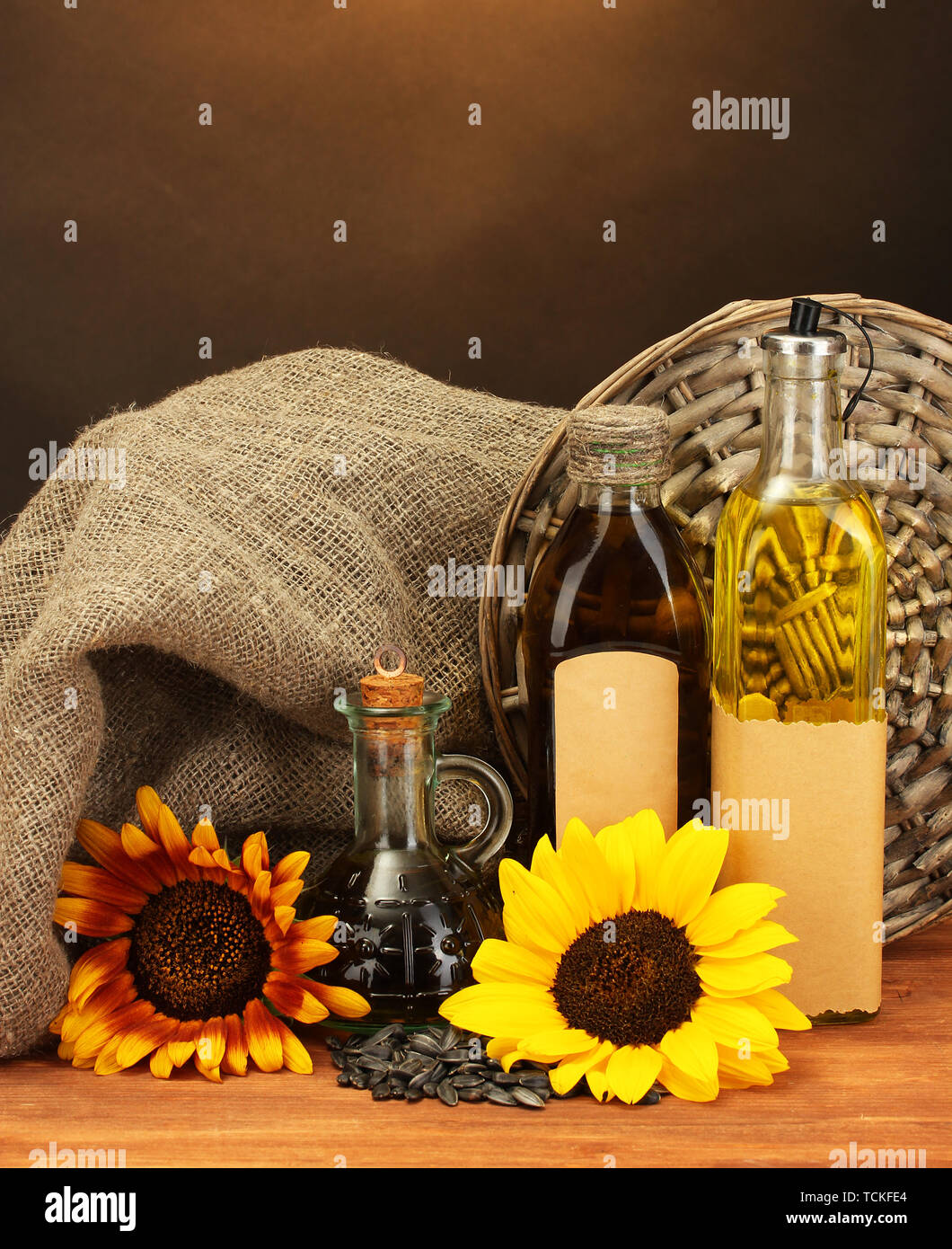 En bouteilles d'huile, de tournesol et de graines, sur table en bois sur fond brun Banque D'Images