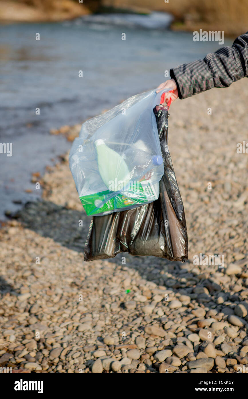 Les déchets dans la nature, le nettoyage de l'environnement au printemps sur la rivière à partir de la poubelle une femme en bleu à usage unique en latex à grand bleu en mitaines Banque D'Images