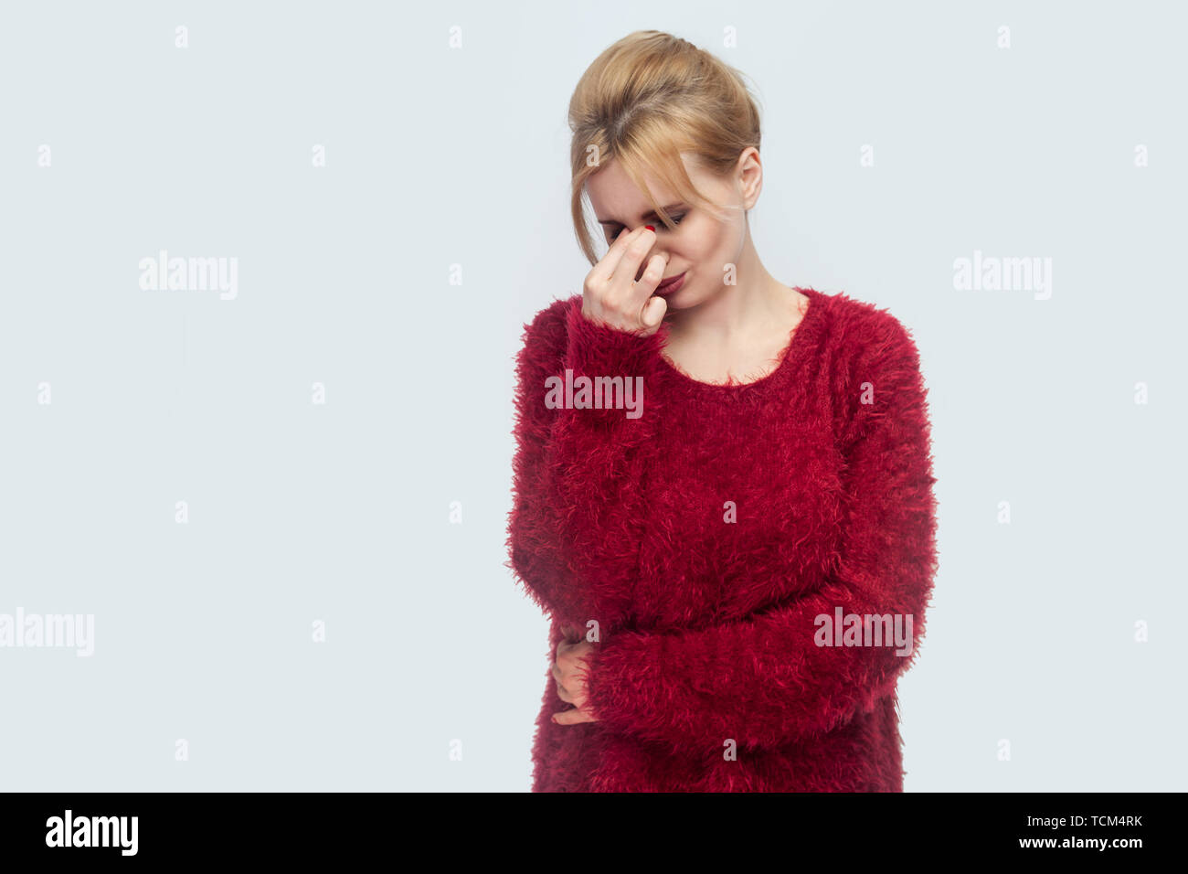Portrait de seul triste ou fatigué belle jeune femme blonde en blouse rouge debout, tenant la tête en bas, et de pleurer avec difficulté et sans espoir. Piscine stud Banque D'Images