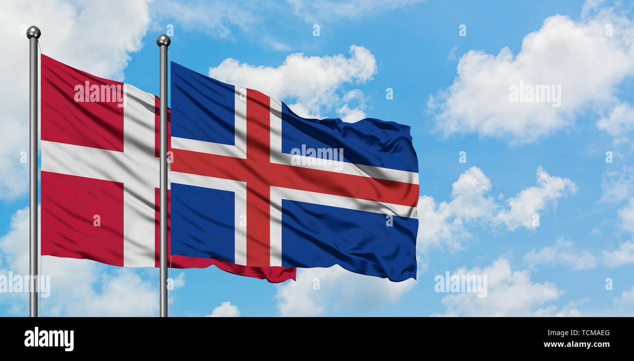 Le Danemark et l'Islande drapeaux dans le vent contre ciel bleu nuageux blanc ensemble. Concept de diplomatie, de relations internationales. Banque D'Images