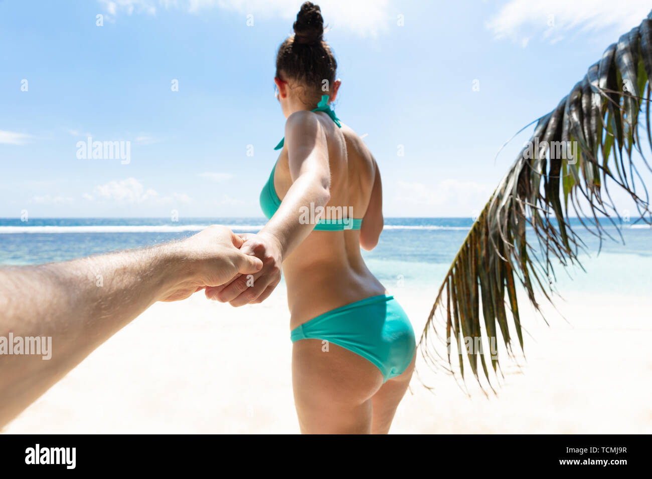 Jeune femme tenant la main de son petit ami en allant vers la mer à la plage Banque D'Images