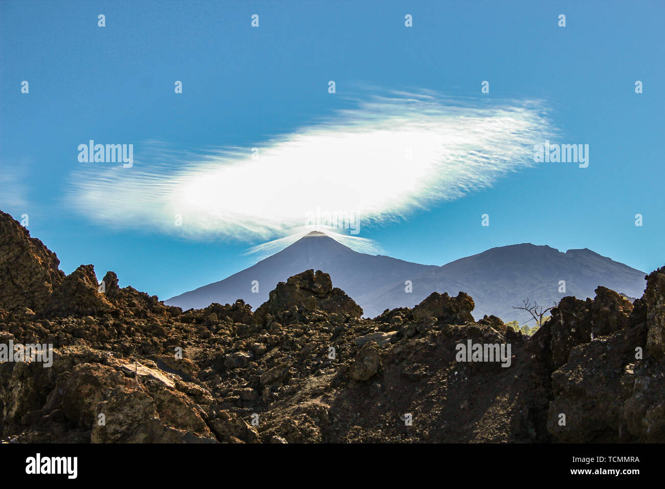 Pierres de lave couvertes par la vallée. Pico del Teide montagne neige blanche avec taches, en partie couvert par les nuages. Ciel bleu. Le Parc National du Teide, Tene Banque D'Images