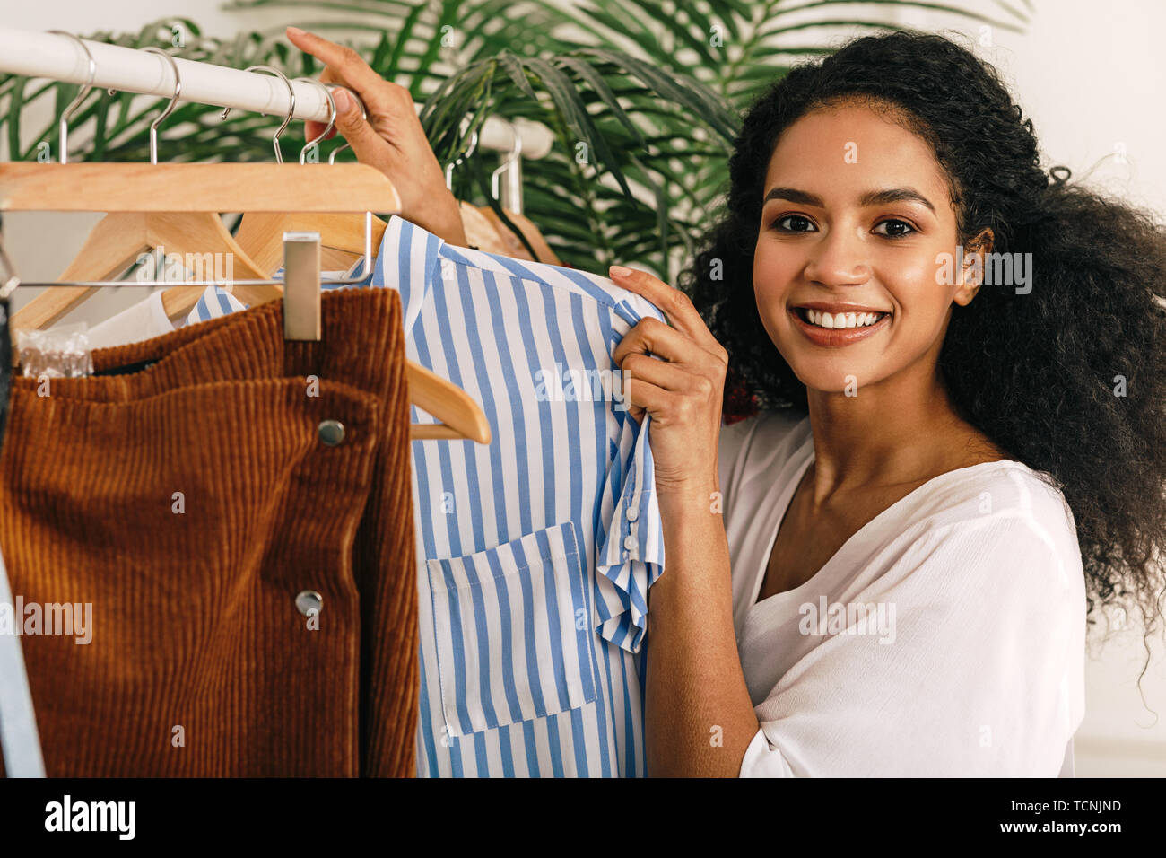 Happy woman clothes rack et holding shirt Banque D'Images