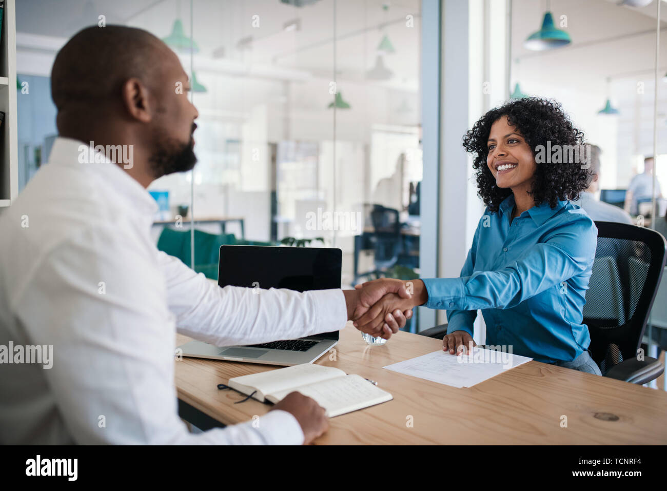 Smiling African American manager assis à son bureau dans un bureau en serrant la main d'un demandeur d'emploi après une entrevue Banque D'Images