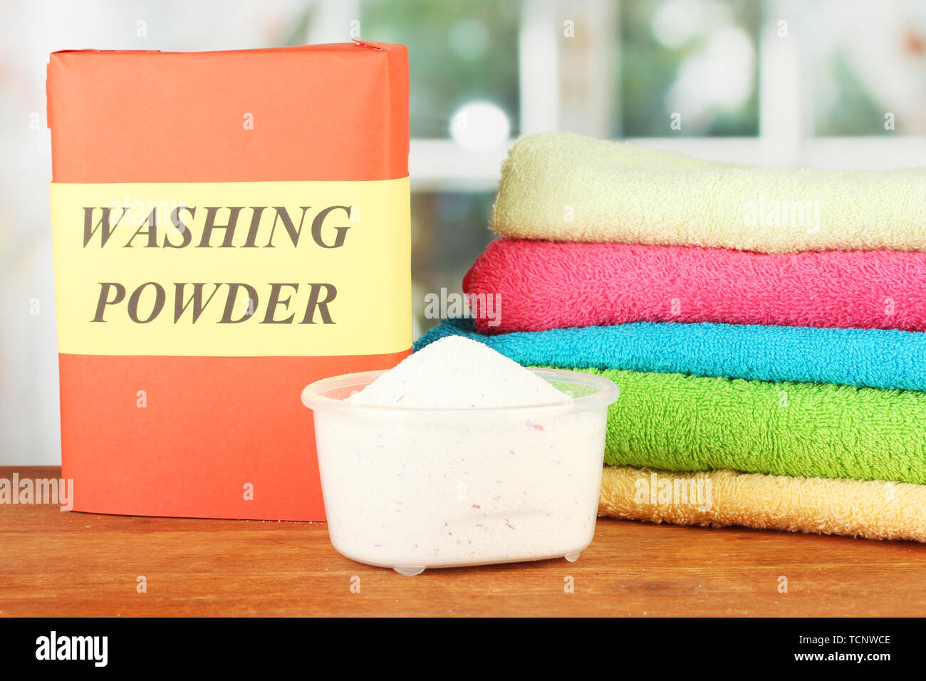 Fort de lessive avec blue tasse à mesurer et les serviettes, sur table en bois close-up Banque D'Images