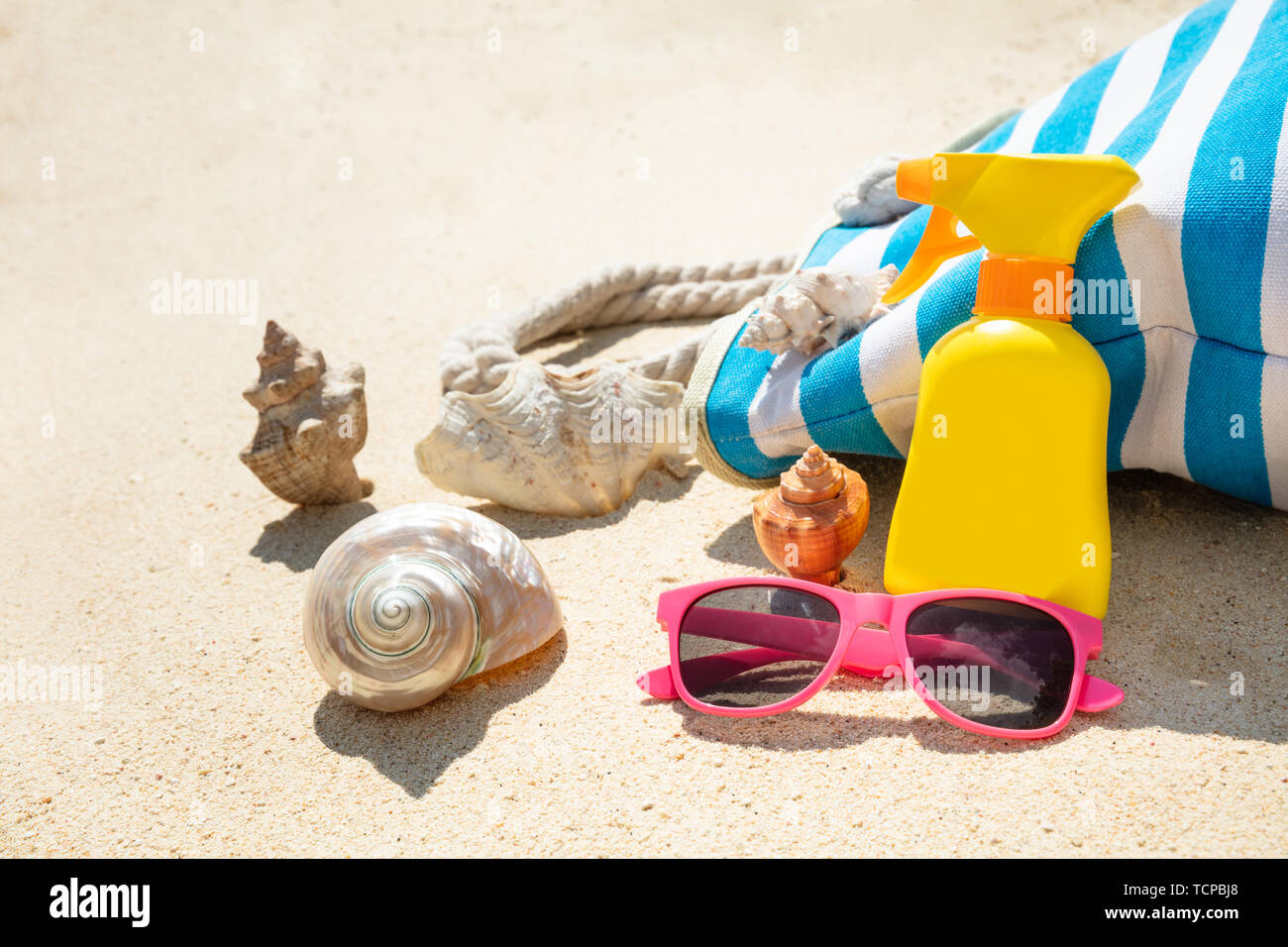Lunettes de soleil, crème solaire, de coquillage et de sacs à main On Beach Banque D'Images